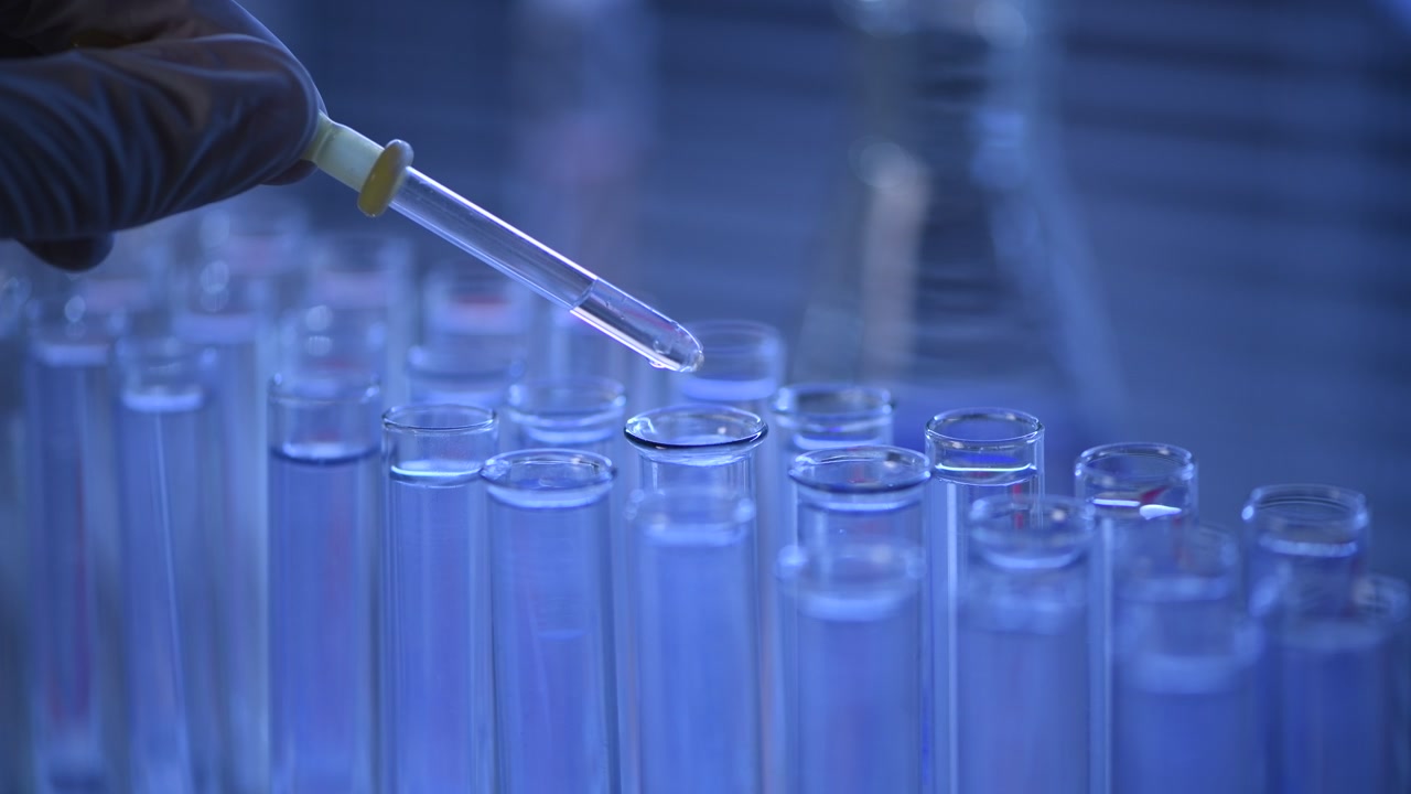 Primo piano di un contagocce che aggiunge liquido a una provetta in laboratorio