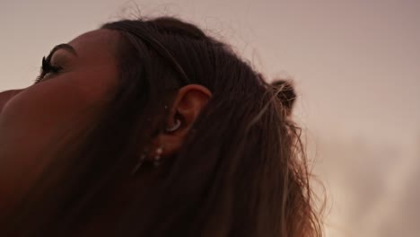 Slow-motion-cinematic-shot-of-a-beautiful-model-fixing-her-hair-with-the-sun-setting