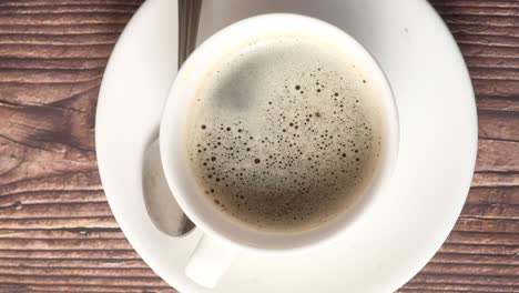 una taza de café negro en una mesa de madera