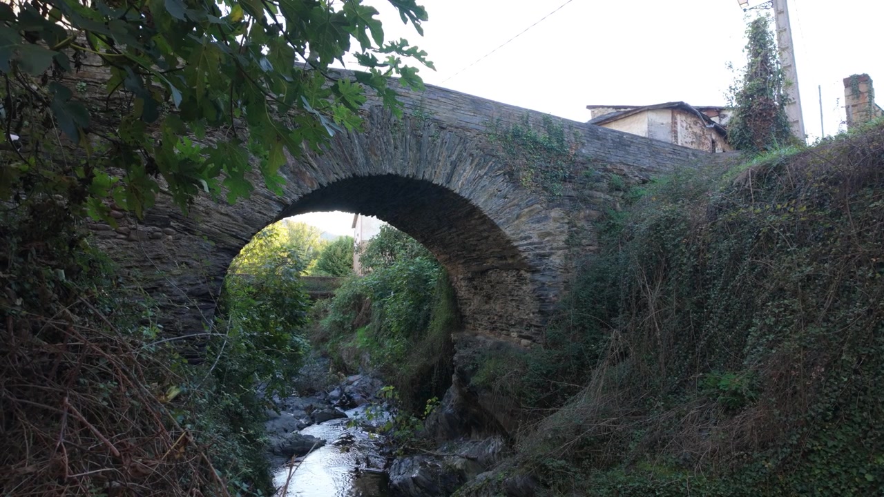 Arco di ponte romano in pietra che attraversa un ruscello stretto a Éntoma, O Barco de Valdeorras, Galizia