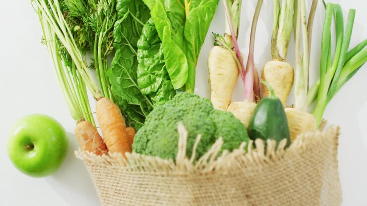 Video of fresh vegetables and apple in rustic bag over white background