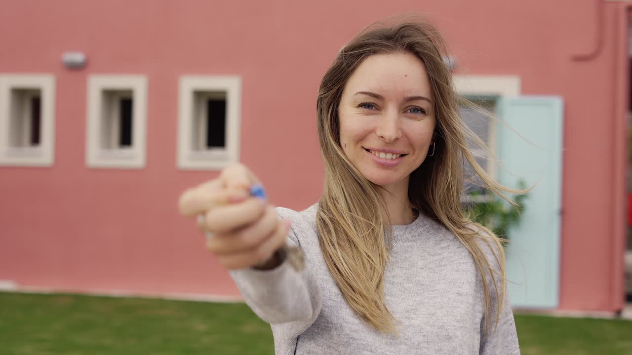 dama satisfecha mostrando las llaves del nuevo apartamento fuera de la nueva casa