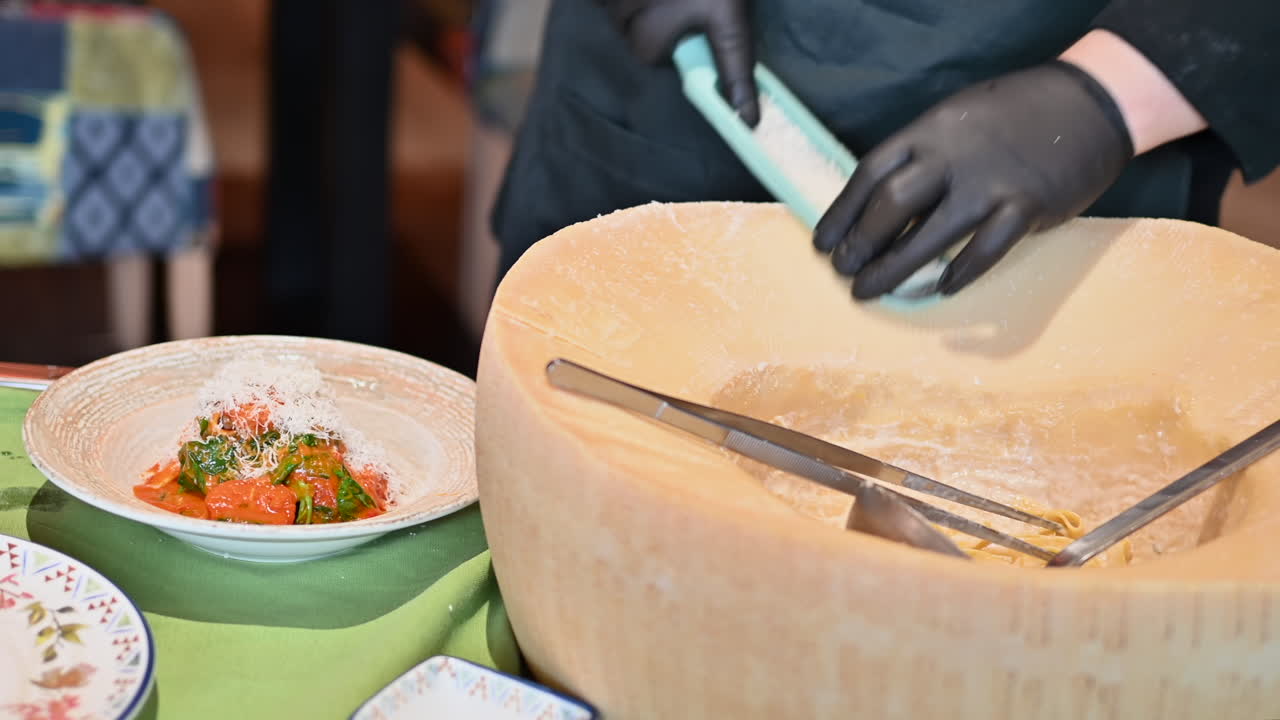 Man putting grated parmesan on pasta in a restaurant
