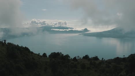 drone aerial view, flying over trees, revealing beautiful blue lake atitlan, guatemala