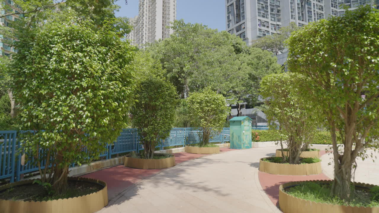 Recuo de dolly passando por arbustos arredondados e árvores ornamentais no parque de Hong Kong.