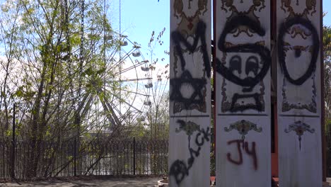 an abandoned and graffiti covered ferris wheel at an amusement park presents a spooky and haunted image