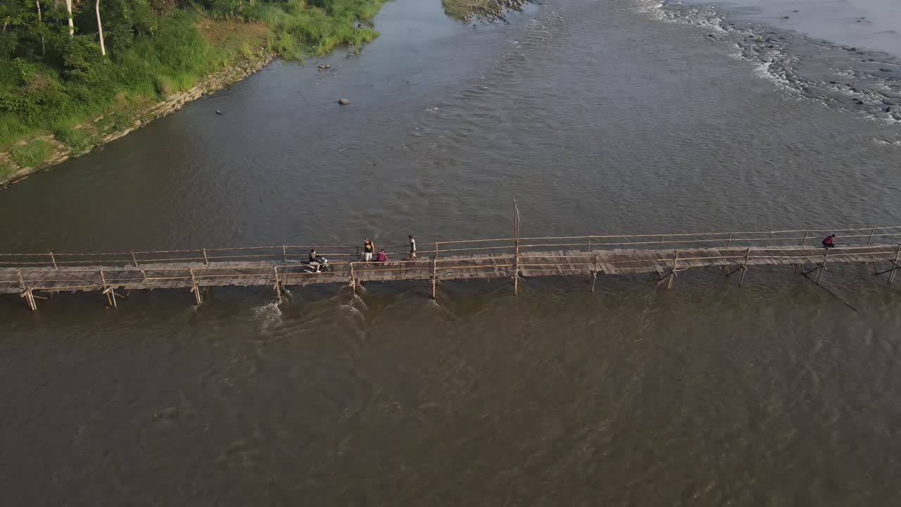Aerial footage shows a wooden bridge spanning the Progo River, passable by motorbikes. As a link between the villages of Bantul and Kulonprogo.
