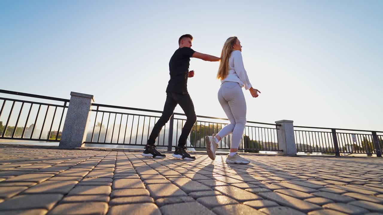 Street dance of young couple. Young couple performing freestyle dance in front of river
