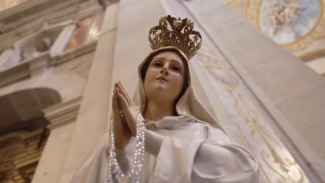 low angle of virgin mary statue holding rosary with crown inside church