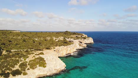 a forward panning shot showing the cliff line at the cala varques beach among a massive landscape and stunning blue water in majorca, spain