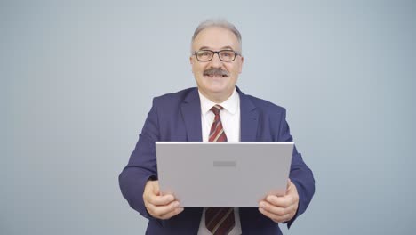 el hombre de negocios satisfecho mira la computadora portátil y aprueba.