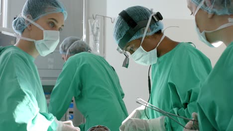 diverse surgeons wearing surgical gowns operating on patient in operating theatre, slow motion