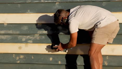 man repairing beach hut at brighton beach