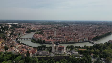 Impresionante-Vista-Aérea-De-Una-Ciudad-Con-Un-Río-Que-La-Atraviesa-Nubes-Esponjosas-Que-Se-Extienden-A-Lo-Largo-Del-Horizonte-Varios-Edificios-De-Diferentes-Tamaños-Y-Formas-árboles-Se-Alinean-En-Las-Orillas-Del-Río-Automóviles-En-La-Carretera