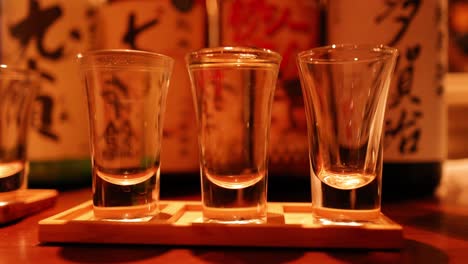 sake glasses being filled on wooden stand