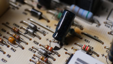 a capacitor, resistors and many other electronic components on an old retro circuit board controller