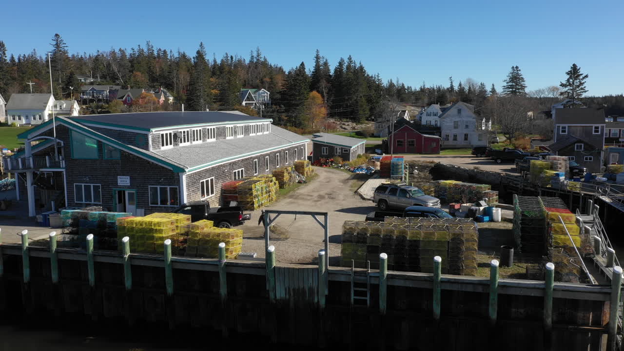 vinalhaven, fox islands, knox county maine, usa에 있는 바다가재 어업 창고에서 바다가재 덫을 끌고 있는 남자의 드론 영상으로 공중 비행