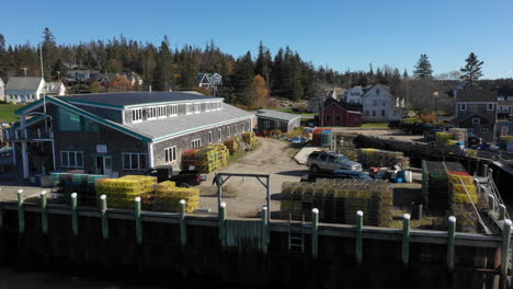 aerial fly by drone footage of man dragging lobster traps at lobster fishery warehouse in vinalhaven, fox islands, knox county maine, usa