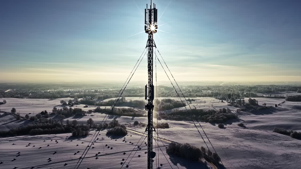 Vista aerea di un'antenna per cellulari in un paesaggio innevato con un sole splendente in inverno.