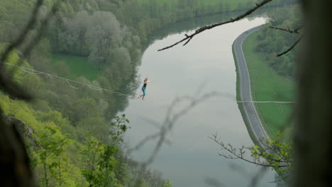 Female-athlete-on-high-line-slack-line-over-river-in-Germany-at-sunset