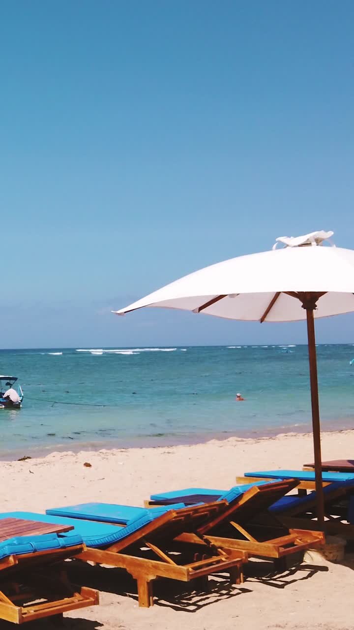 Sdraio da spiaggia tropicale sotto l'ombrellone Paesaggio marino verticale mare blu.