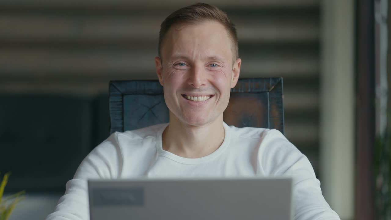 Portrait of smiling young man sitting at laptop in the room