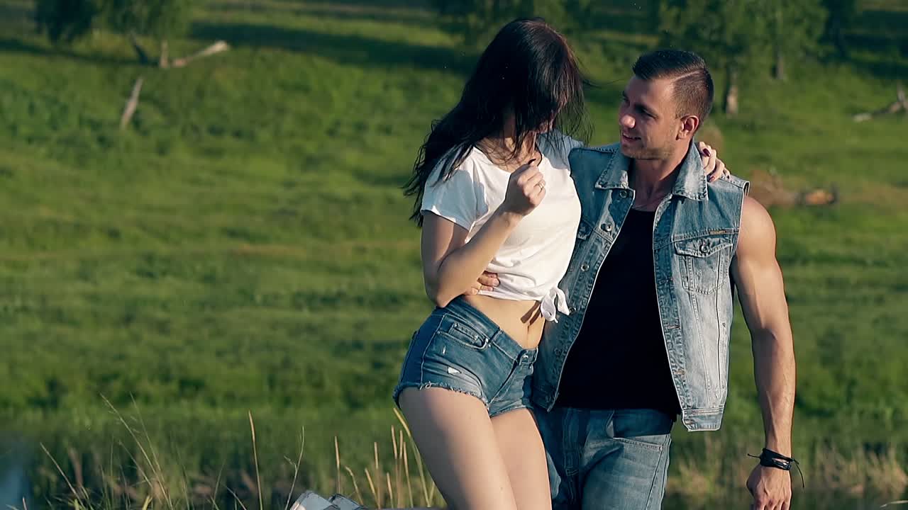 예쁜 남자가 예쁜 갈색 여자를 팔에 들고 회전합니다.