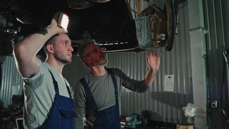 car mechanics inspecting undercarriage