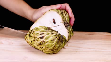 slicing a custard apple to reveal seeds inside