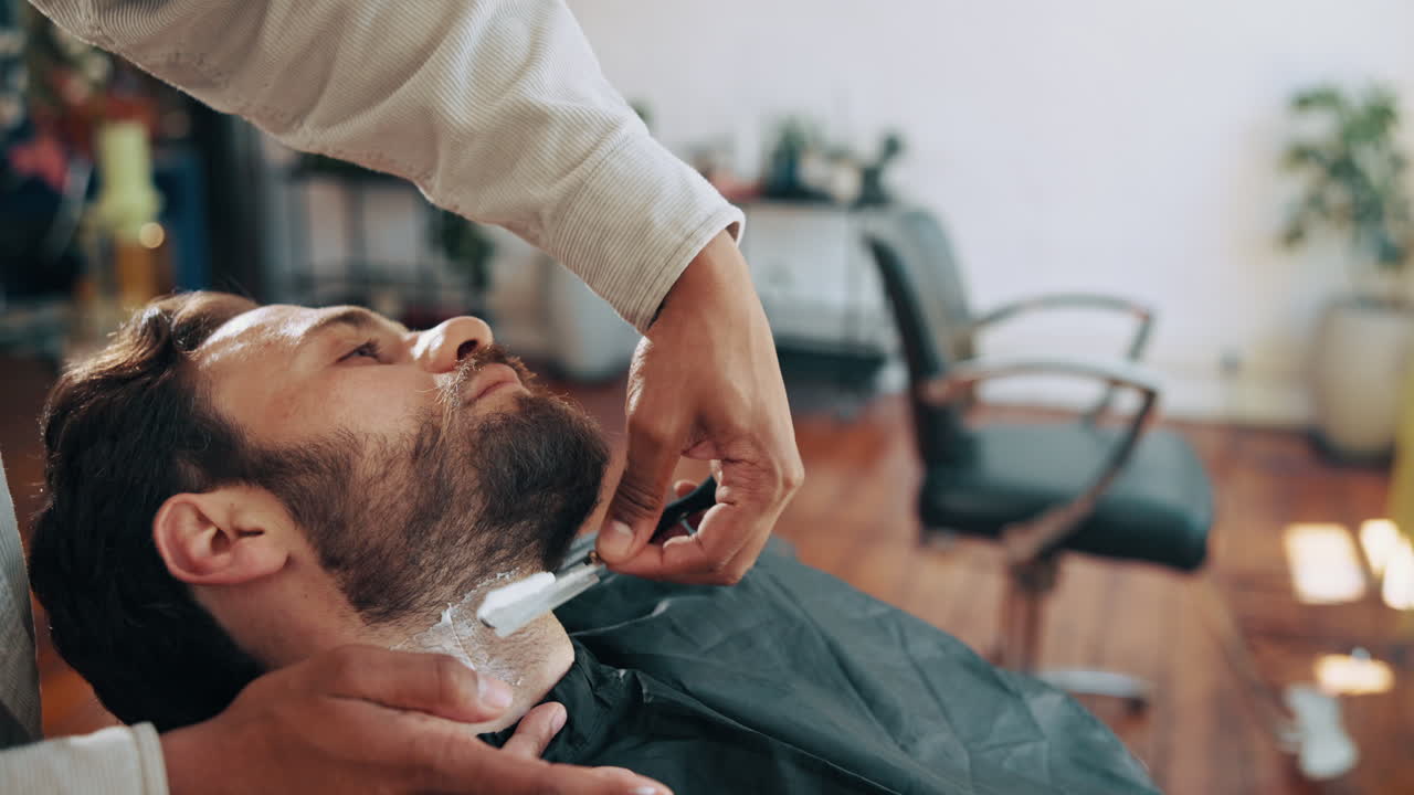 Barber Shaving Man's Beard with a Straight Razor in a Barbershop