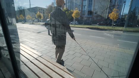 visually impaired man crossing the road with his stick with the help of tactile pedestrian sidewalk for the visually impaired in the city.