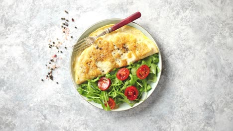 classic egg omelette served with cherry tomato and arugula salad on side