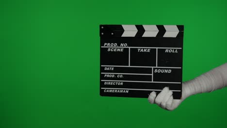 clapperboard held by a mummy figure on a green screen