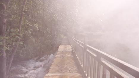 Walking-Through-Mist-On-Bridge-of-Water-Source-of-Whisky-Distillery-in-Yunnan,-China