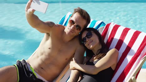 hombre tomando una foto de sí mismo con su esposa en la piscina