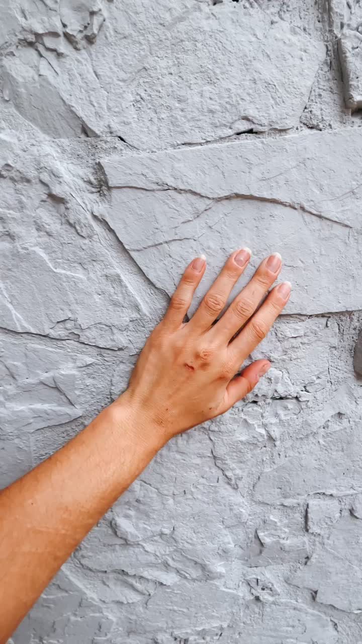 mano tocando una pared gris con textura