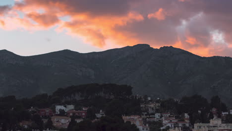 Zoom-En-Timelapse-De-Enormes-Nubes-Moviéndose-Rápido-Sobre-Y-Detrás-De-Una-Montaña-Durante-La-Puesta-De-Sol