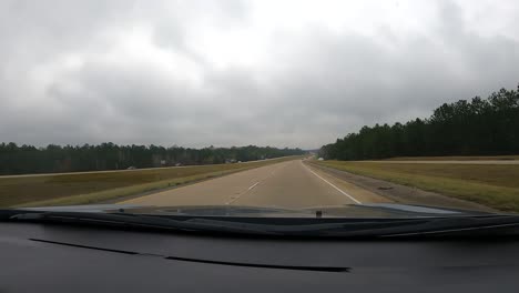 Driving-along-a-highway-in-the-forested-countryside-on-a-dreary,-overcast-day---point-of-view-hyper-lapse