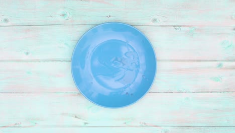 slices of watermelon appear and disappear from blue plate on wooden table. stop motion