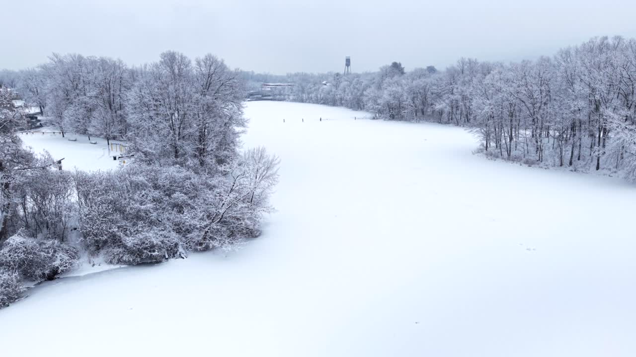 Lower Mill Pond i Easthampton, MA, med frossent vand, rimfrostklædte træer og faldende sne om vinteren. Droneoptagelse med tilbagetrækning