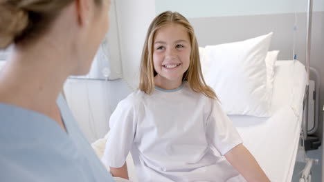 doctora caucásica hablando con una paciente feliz sentada en una cama de hospital, en cámara lenta