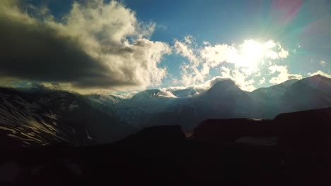 aerial view of sun rays through a cloudscape over austrian mountains snowy summit