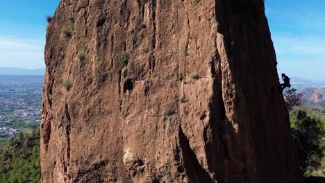 Man-rock-climbing-aerial-view-of-sportsman-rapelling-mountain-in-La-Panocha,-el-Valle-Murcia,-Spain-woman-rapel-down-a-mountain-climbing-a-big-rock