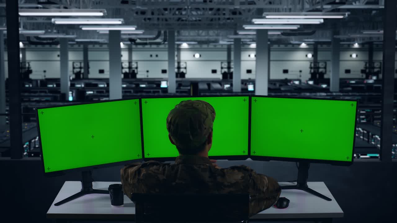 데이터 센터에서 여러 컴퓨터 모니터를 모방하는 동안 스트레칭하는 피곤한 아시아 군대의 뒷면