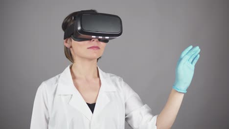 Feale-Arzt-Führt-Experimentelle-Medizinische-Eingriffe-Durch-Und-Trägt-Ein-Virtual-Reality-Headset,-Isoliert-Auf-Grauem-Hintergrund.-Modernes-Gesundheitskonzept.-In-4k-Gedreht