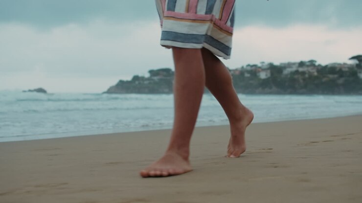 Ragazza sconosciuta che cammina lungo la spiaggia. Donna a piedi nudi che trascorre le vacanze in spiaggia.