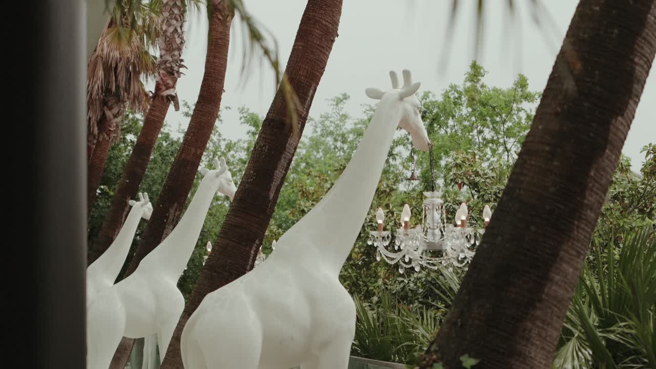 stylized giraffe statues and chandelier in lush tropical garden