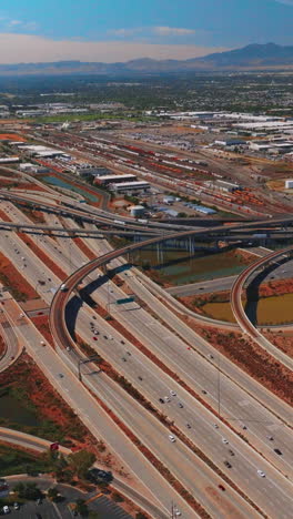 plexus of roads and skyways at outskirts of salt lake city on sunny day. mountains at backdrop. aerial perspective. vertical video