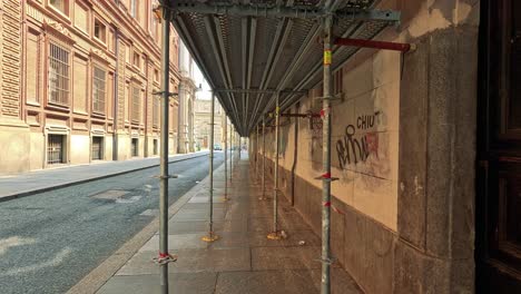 exploring a graffiti-lined footpath under scaffolding