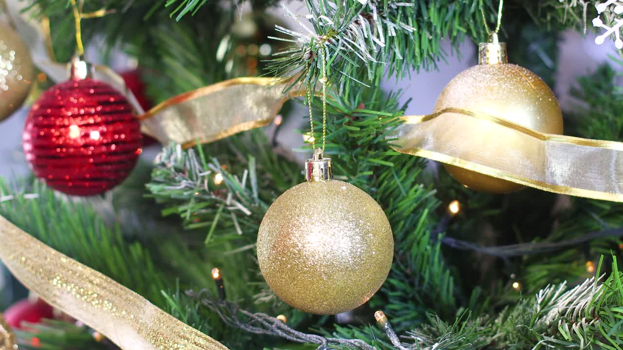 cerca de la mano de la mujer poniendo ornamento de brillo dorado en el árbol de navidad